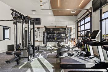 A gym with a variety of equipment including treadmills, weights, and exercise machines.